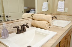 A close up of two modern bathroom sinks, with rolled towels.