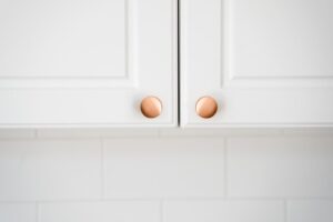 walterworks hardware two copper knobs on white cabinet doors